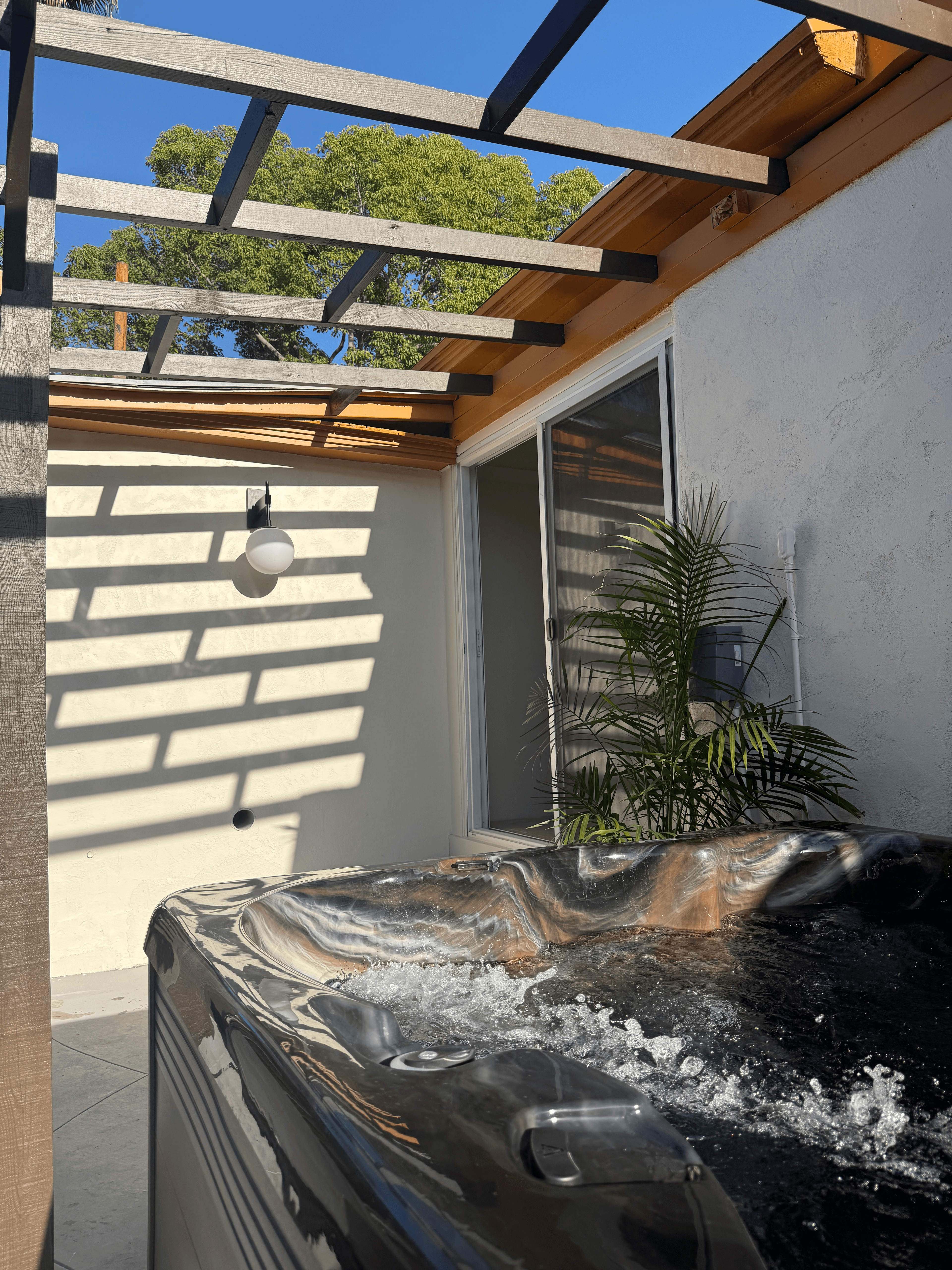 Hot tub under wood pergola with tropical plants