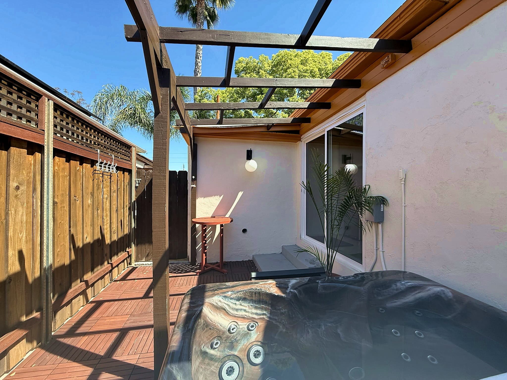 Hot tub under wood pergola with tropical plants